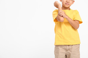 Little boy scratching himself on white background