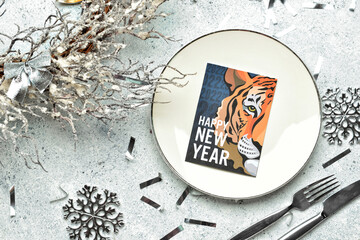Table setting with greeting card for New Year 2022 celebration on light background