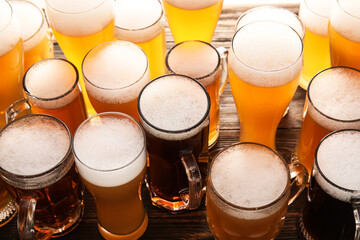 Mugs and glasses of cold beer on wooden background. Oktoberfest celebration