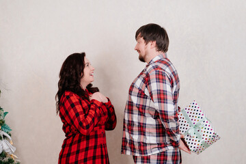 a man in plaid red pajamas makes a gift to a woman.