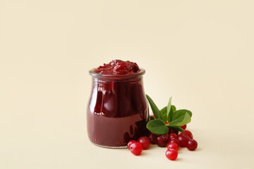 Jar with tasty cranberry jam and berries on color background