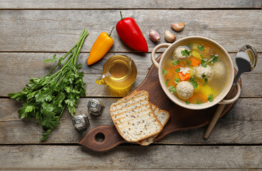 Bowl with tasty meatball soup, bread and spices on wooden background