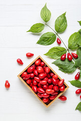 Branch and box with fresh dogwood berries on white wooden background