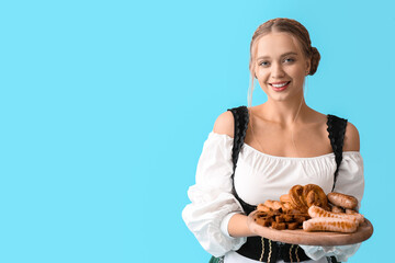 Beautiful woman in traditional German costume and with snacks on color background