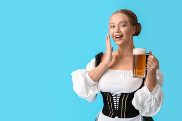 Excited woman in traditional German costume and with mug of beer on color background