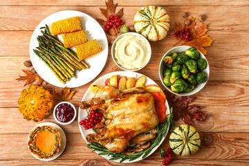 Tasty baked turkey and different food for Thanksgiving Day on wooden background