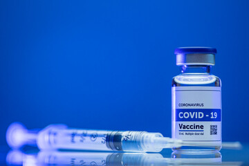 Covid vaccine syringe and vile on blue background