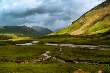 Landscape with a river. Serine green meadow landscape high up in the Himalayas on Great Lake of  Kashmir trek. valley. Mountains in Gangabal Lake vicinity, Kashmir India.