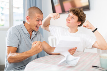 Obraz premium Joyful father and son cheering after reading a letter from college