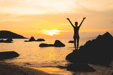 Lady's silhouette with raised arms against sunset