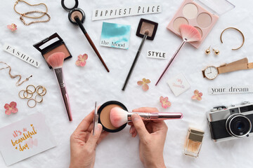 Makeup flatlay with female hands using face bronzer