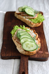 Sandwiches with chicken meat, cucumber, lettuce  and soft cheese on wooden board. Selective focus