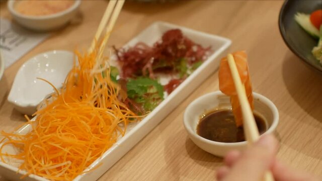 4k video of using chopctick pick slamon sashimi dipping into soy sauce, raw fish Japanese style food.