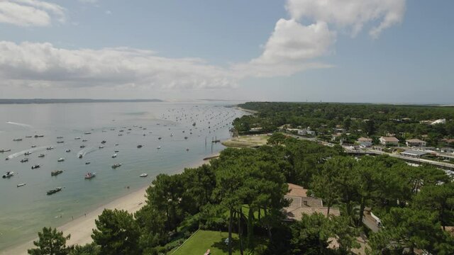 Oyster fishing village of Le Canon at Cap Ferret in Arcachon Bay France with hundreds of fishing boats left, Aerial flyover shot