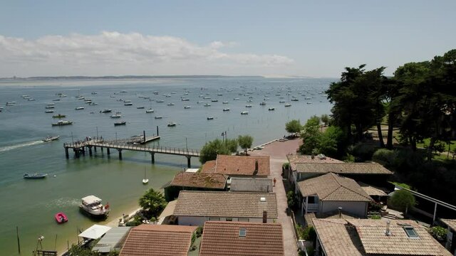 Le Canon oyster fishing village in Arcachon Bay France with terracotta tile rooftops and boats, Aerial flyover rising shot