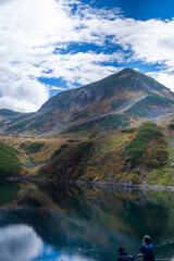Fototapeta premium 富山県立山町の立山の秋の紅葉の季節に登山している風景 Scenery of climbing Tateyama Mountain in Tateyama Town, Toyama Prefecture, Japan during the season of autumn leaves. 