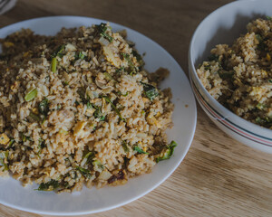 Stir fried rice with chicken ,kale ,onion, egg in a white plate on the wood table for cooking.