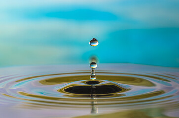 Fototapeta na wymiar Water droplet splash and make perfect ripples on water surface with blue background.
