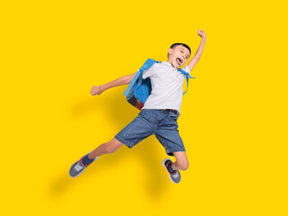Happy student boy jumping.Isolated on yellow background.