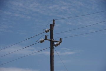 Simple rural electricity distribution pylon and power lines under blue sky