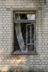 Old rusty security bars on a broken window in a brick wall.