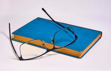 Glasses was taken off and put on a blue book. White background