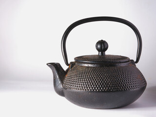 Black cast iron teapot on a white background.
