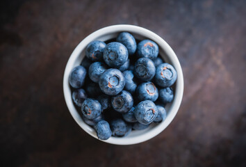 Blueberries in ceramic bowl on rustic wooden background. Selective focus. Shallow depth of field.