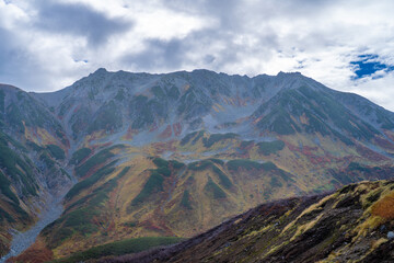 Fototapeta premium 富山県立山町の立山の秋の紅葉の季節に登山している風景 Scenery of climbing Tateyama Mountain in Tateyama Town, Toyama Prefecture, Japan during the season of autumn leaves. 