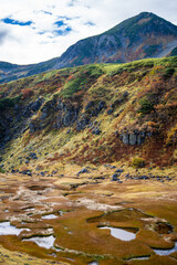Fototapeta premium 富山県立山町の立山の秋の紅葉の季節に登山している風景 Scenery of climbing Tateyama Mountain in Tateyama Town, Toyama Prefecture, Japan during the season of autumn leaves. 