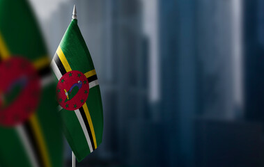 Small flags of Dominica on a blurry background of the city