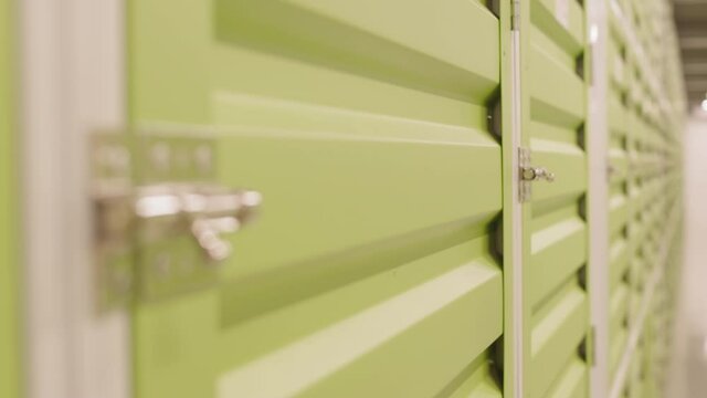 Racking focus of latch on one green self-storage door in long row