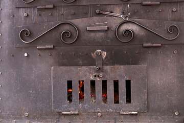 Close-up of a smoking wood-fired iron oven ready for cooking
