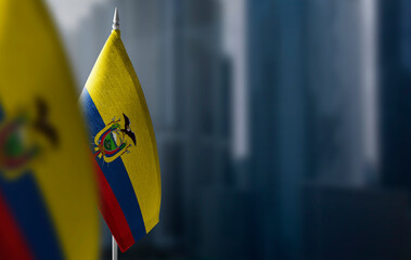 Small flags of Ecuador on a blurry background of the city - obrazy, fototapety, plakaty