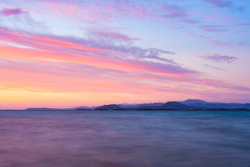 Fototapeta premium Stunning seascape with a romantic and relaxing sunrise reflected on a calm water flowing in the foreground. Golfo Aranci, Sardinia, Italy.