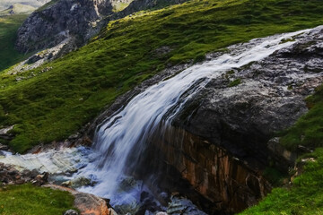 Fototapeta na wymiar gorgeous large waterfall over a dark rock in a green mountain landscape