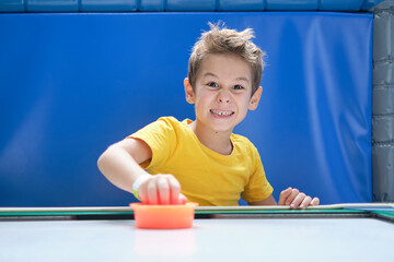 boy intently and enthusiastically play table hockey.. A child who has won his air hockey game, with...
