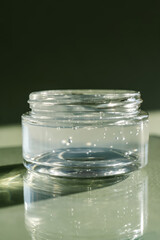 Transparent gel in a jar on a green background.