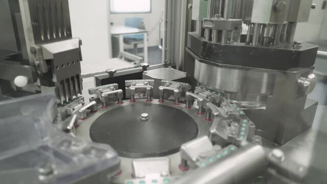 Production of pharmaceuticals and drugs, large number of capsules in motion, white tablets on the conveyor, medical production equipment.