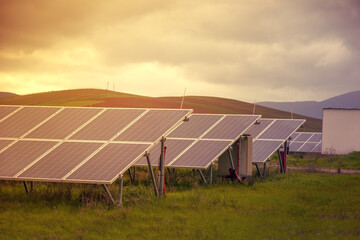 Energy storage system. Photovoltaics solar panels in power station, alternative energy from the sun in field with green grass and mountains at the horizon