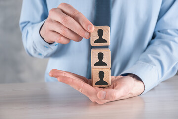 Businessman hold and put wooden cube block shape with user icon on grey table. Space for text. Internet icons interface foreground. global network media concept,contact on virtual screens ,copy space