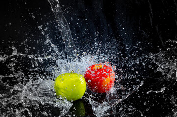 Juicy apples in spray of water in the dark on a black photo. The frozen moment. Explosion of water and freshness