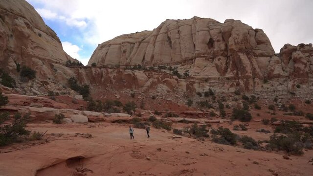 Couple of Hikers Walking in Desert Landscape of Capitol Reef National Park, Utah USA, Wide View