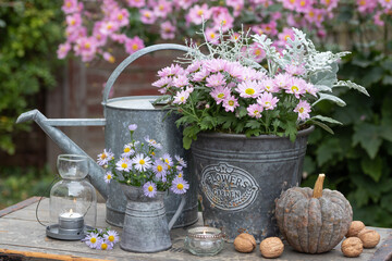 vintage Gartendekoration mit Herbstblumen, Kürbis und Windlichtern