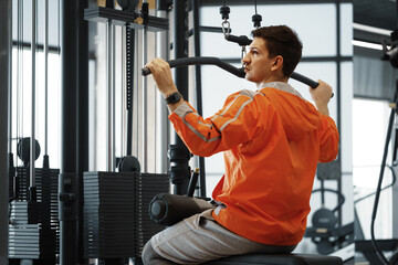 Young man working out training back muscles in the gym