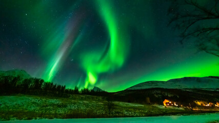 Fototapeta na wymiar wundervolle Nordlichter in Troms in den Lyngenalps. begeisterndes Lichtspiel am nächtlichen Himmel, über einer beleuchteten Farm in Lakselvdal. Aurora Borealis bei Tromsö, Norwegen