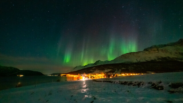 Nordlichter wie eine Krone über Lakselvbukt in den Lyngenalps, Norwegen. Aurora Borealis over snowy mountains. village on illuminated night © Dieter