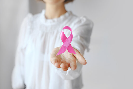 Unrecognized Female In White Blouse Holding Flying Pink Ribbon. Breast Cancer Awareness Photo for Support and Health Care