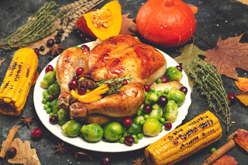 Thanksgiving turkey or chicken for a festive dinner. Food table background with autumn seasonal specialties for Thanksgiving Day. Fried chicken with pumpkin, vegetables and autumn decor on a wooden
