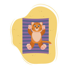 cute tiger lies and basks on the sand, on the beach, on a striped towel
